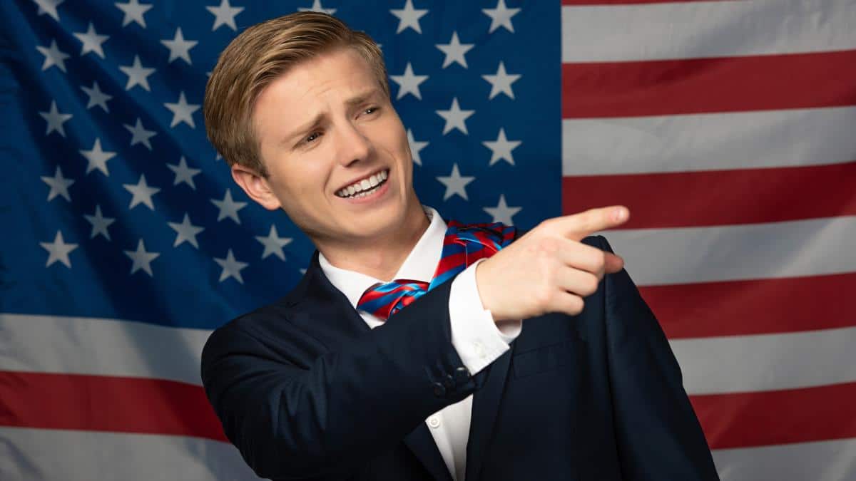 man gestering in front of American flag