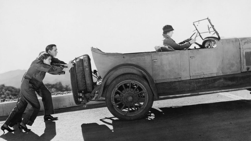 Couple pushing woman in car up hill