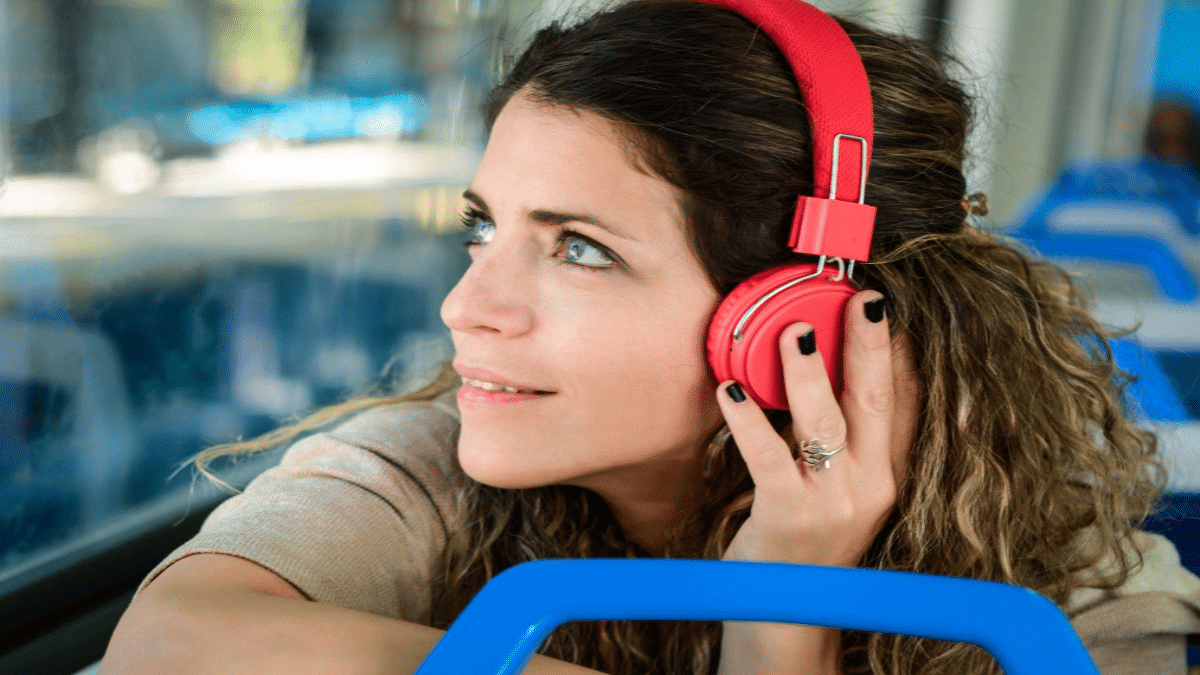 nicomenijes-Young-woman-travelling-by-train-with-red-headphones.png