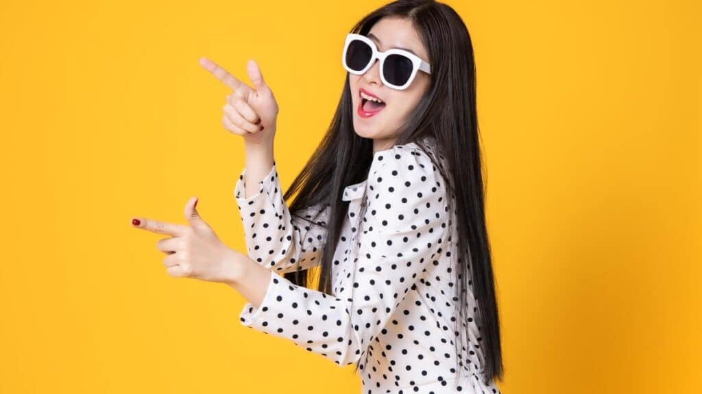 woman pointing fingers yellow background - anon tae Canva
